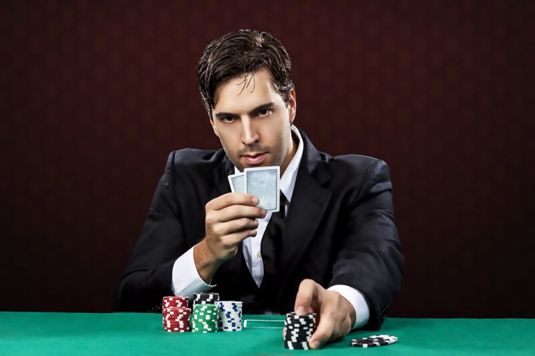 Мужчина игрок в блек-джек с картами и фишками делает ставки