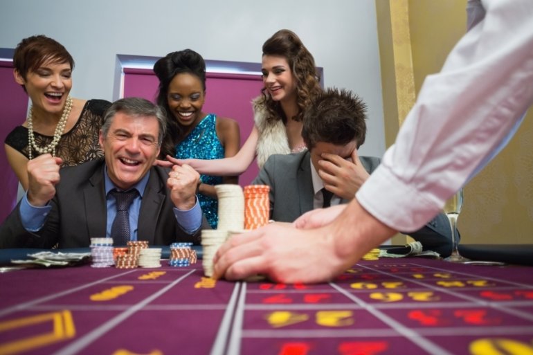 Веселая компания людей разных национальностей за игрой в казино